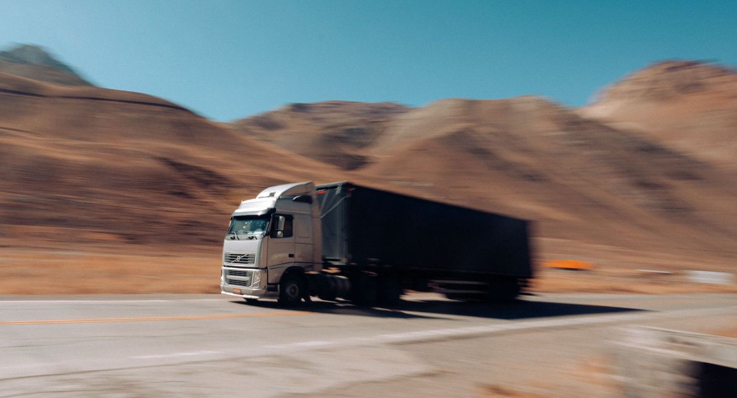 Dynamic shot of a cargo truck speeding along a mountain road in Mendoza Province, Argentina.